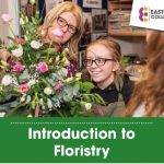 A young person smiles at a bouquet of flowers, an adult stands next to her