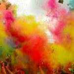 Crowd throwing bright colored powder in the air.